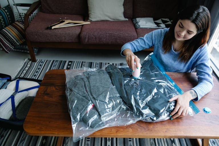 Woman sealing clothes in vacuum bags for efficient packing at home.